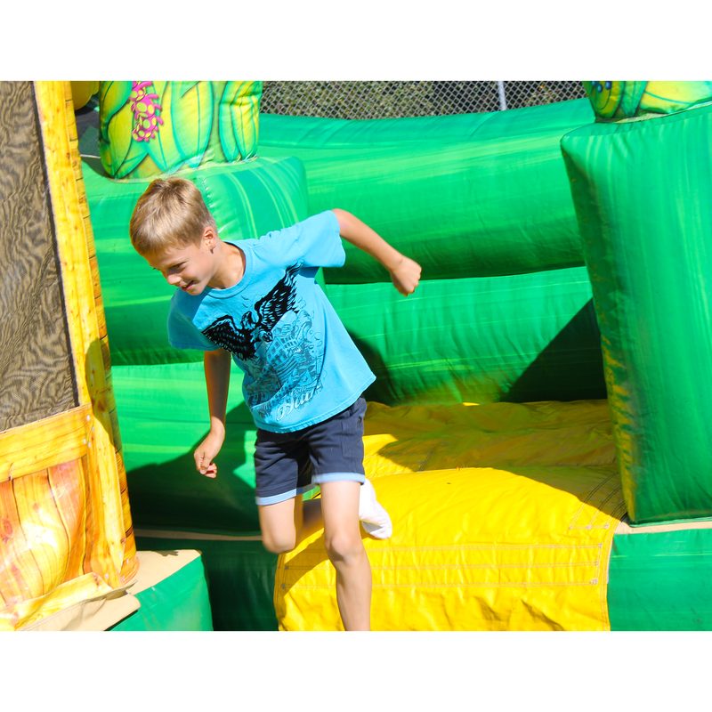 Student jumping in a green and yellow bounce house combo at a school event
