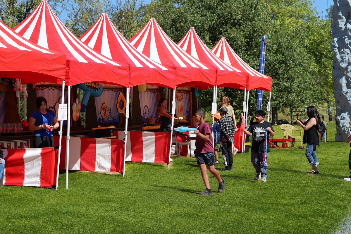 Red and white carnival game booths staffed at a company picnic in Sacramento
