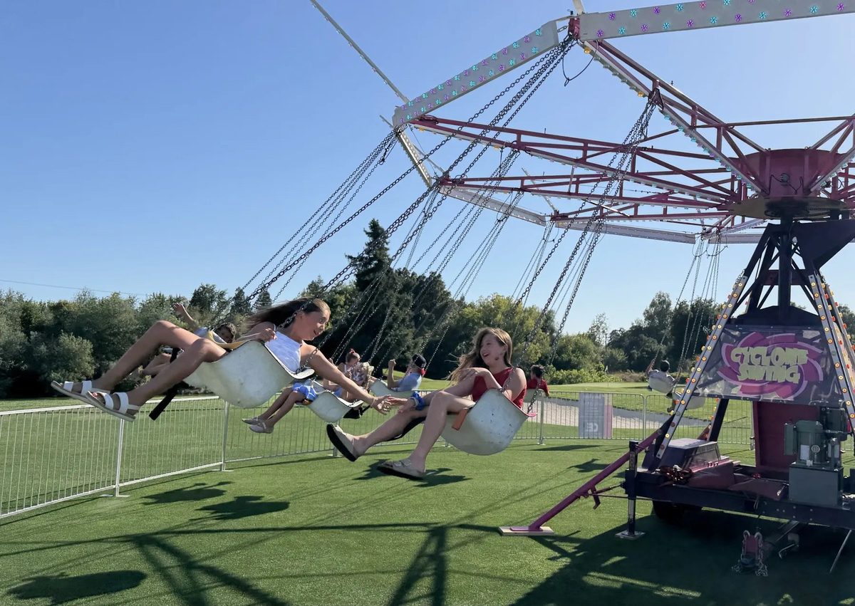 Students riding a carnival swing ride at an outdoor school carnival