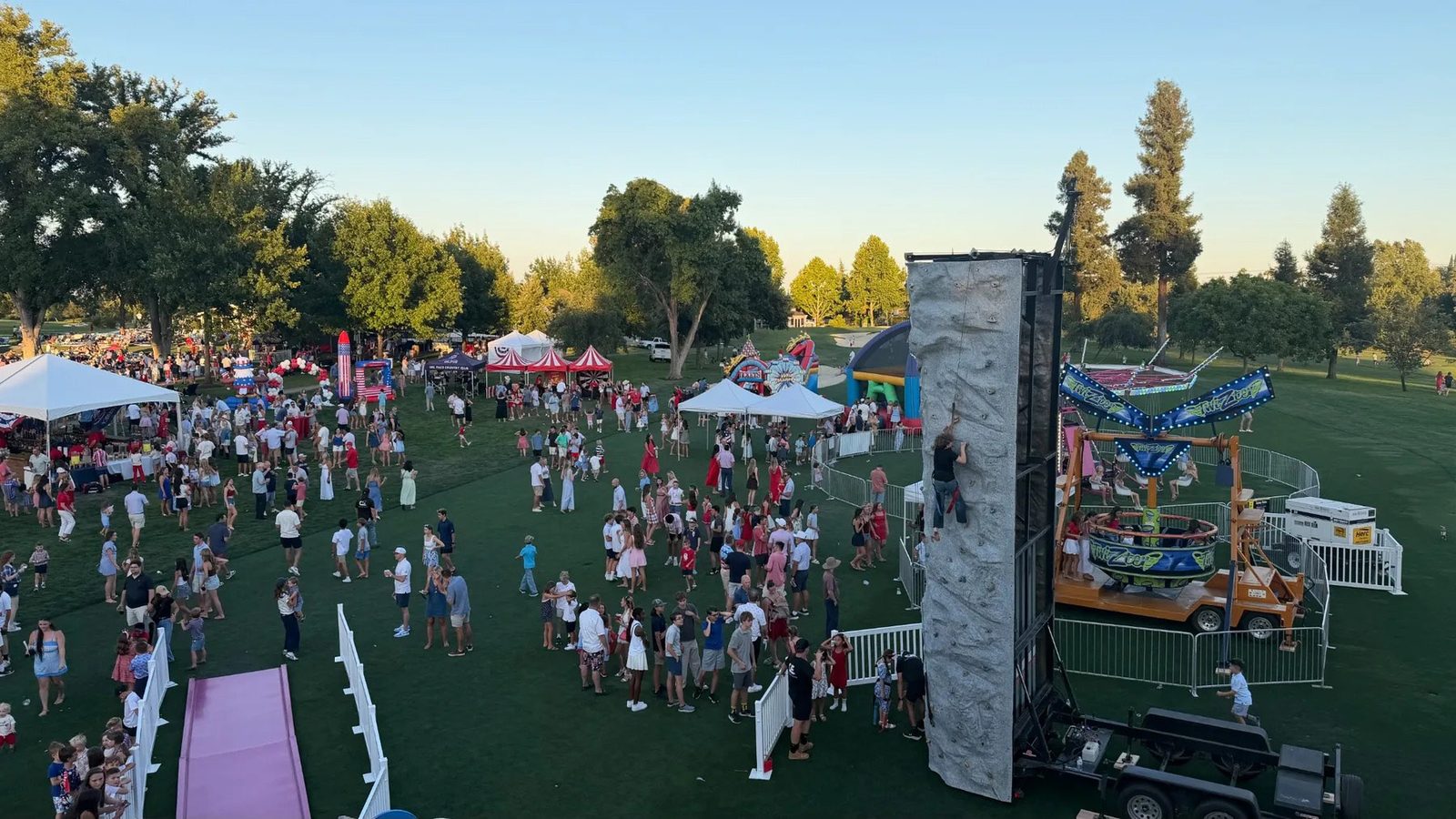 Aerial view of a large company picnic with rock wall, rides, tents, and game zones