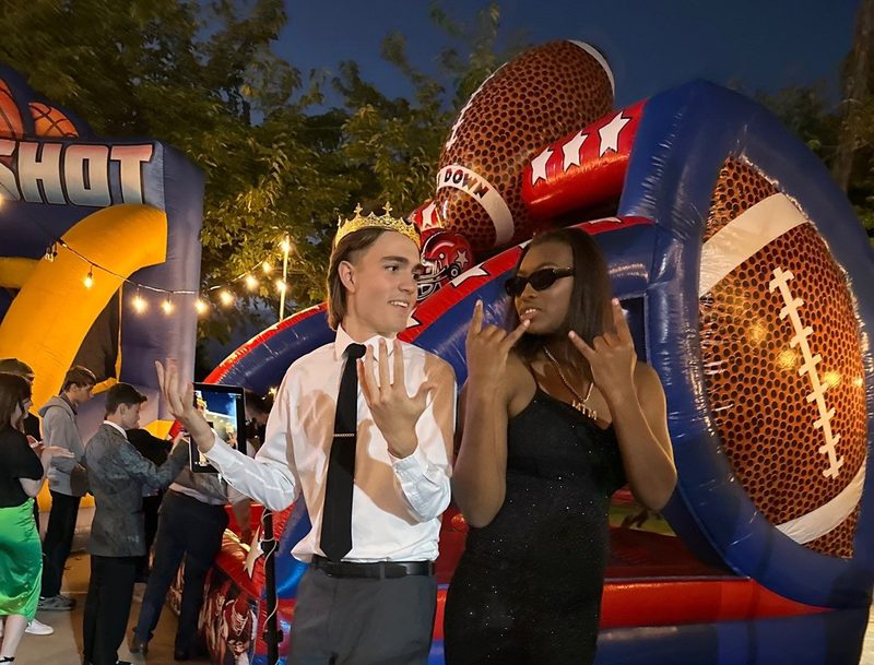 Guests posing with a giant inflatable football photo opportunity at a school event
