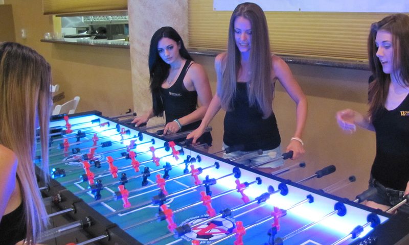 Employees playing a giant LED foosball table at a corporate event