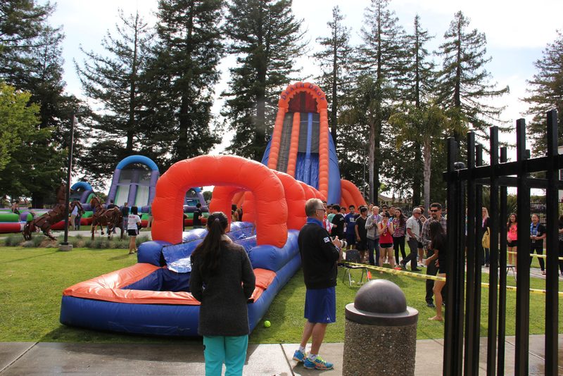 Inflatable slide and carnival games on a lawn at a company picnic
