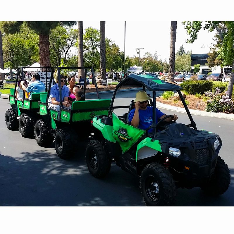 Kids riding a green trackless train at a school event