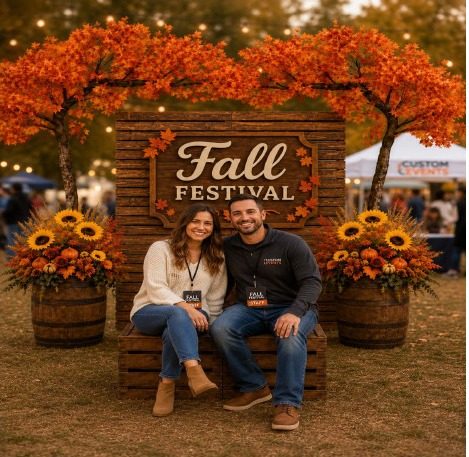 Couple posing at a Fall Festival photo opportunity with autumn trees and sunflowers